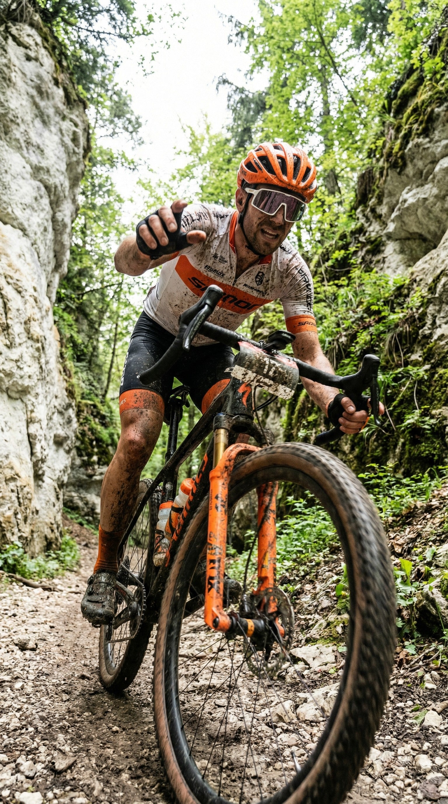 Gravel cyclist racing through rocky forest trail wearing SAOLAR sports sunglasses, muddy terrain, intense effort, dynamic outdoor adventure scene showcasing performance cycling eyewear.