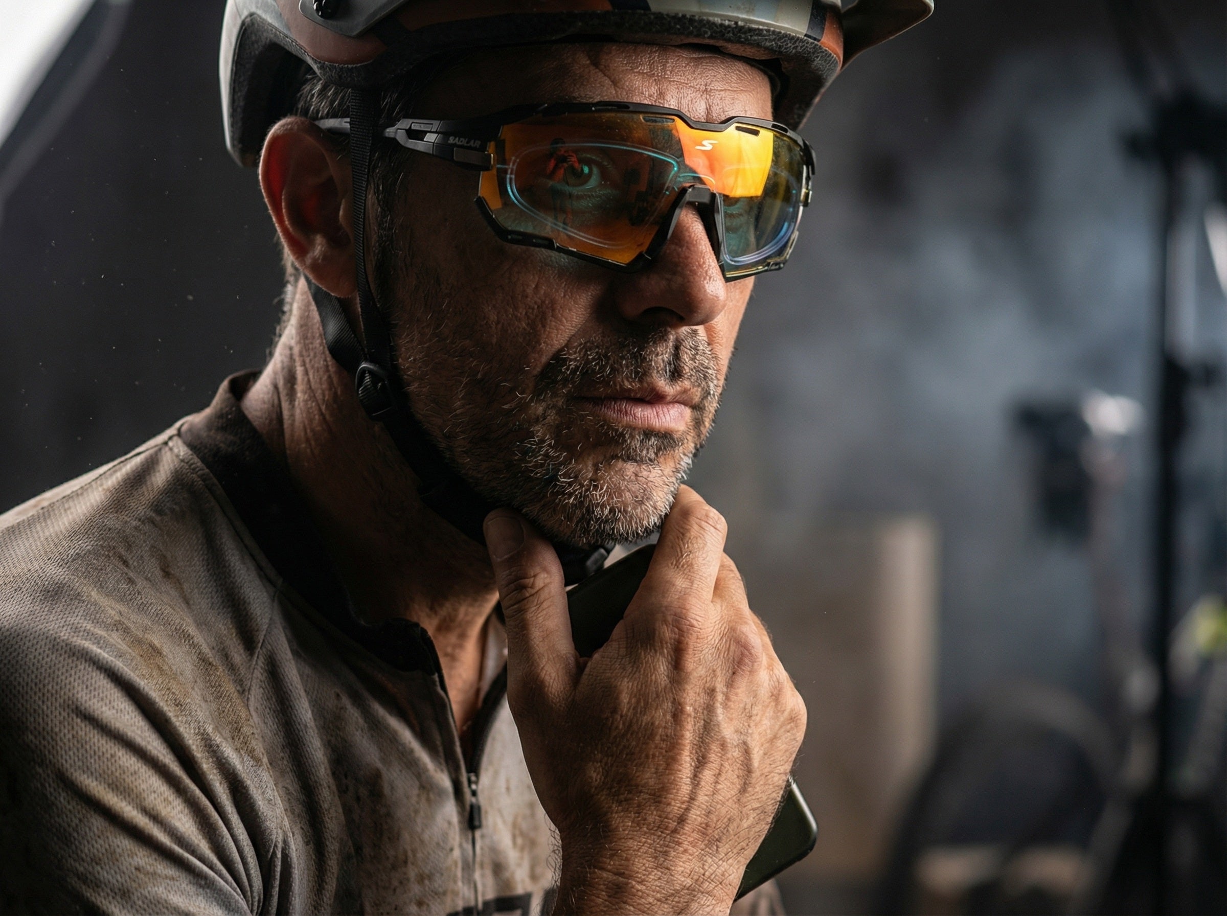 Close-up cyclist wearing wraparound sports sunglasses with visible prescription insert lens, highlighting optical clarity, performance vision, rugged outdoor lighting conditions.