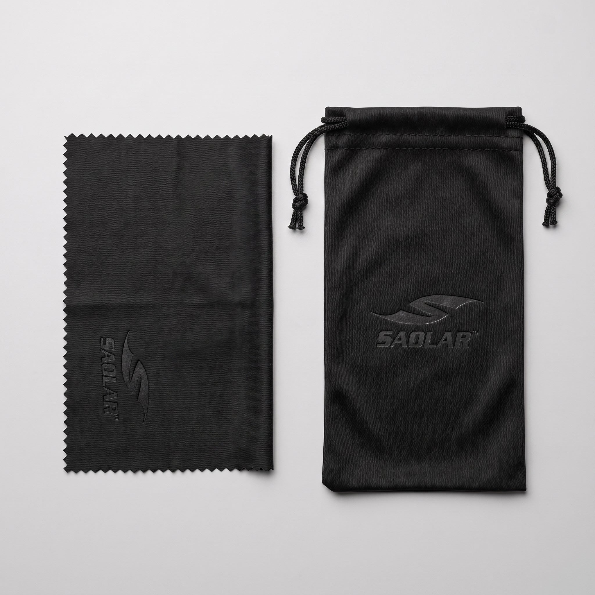 SAOLAR microfiber cleaning cloth and black drawstring sunglasses pouch displayed on a white background. Premium protective accessories feature embossed SAOLAR logos, designed to safely store, clean, and protect cycling sunglasses, sports eyewear, and photochromic lenses from scratches, dust, and everyday wear while traveling or riding outdoors.