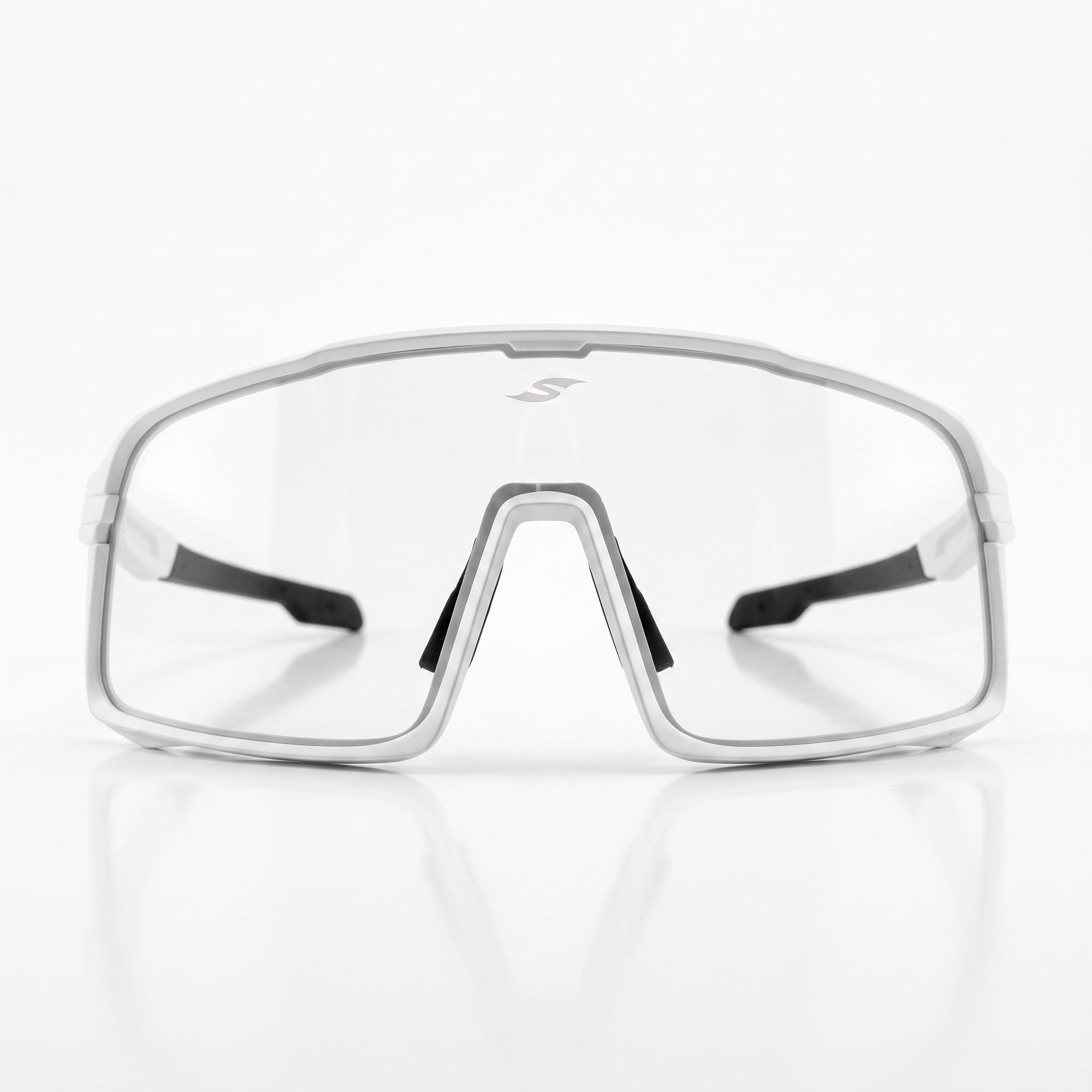 Front view of SAOLAR Shadelane photochromic cycling glasses with a wide clear shield lens and white full-rim frame. The lens spans the face for broad coverage, while black nose pads and temple details add contrast. A small SAOLAR logo appears near the top center of the lens for subtle branding.