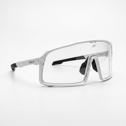 SAOLAR Shadelane photochromic cycling glasses shown in a three-quarter front view. The white performance frame surrounds a large clear wraparound lens designed to adapt to changing light. Black rubber nose pads and temple tips provide contrast, while the angular frame shape and minimalist SAOLAR branding create a clean, technical look.