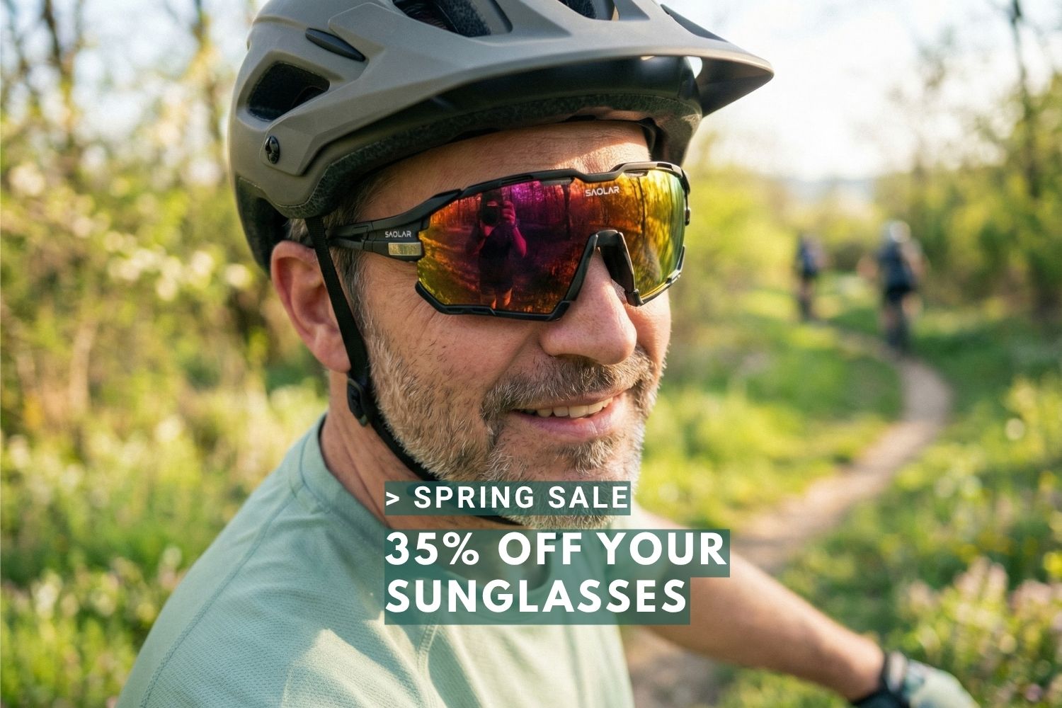 Cyclist wearing SAOLAR sunglasses on sunny spring trail, smiling, with text overlay promoting 35% off spring sale on performance eyewear