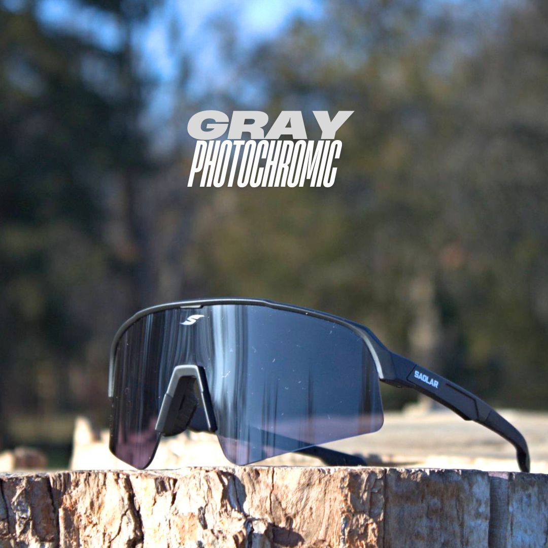 SAOLAR Stratos gray photochromic sunglasses with a black frame and wraparound lens, placed on a wooden stump in an outdoor setting.