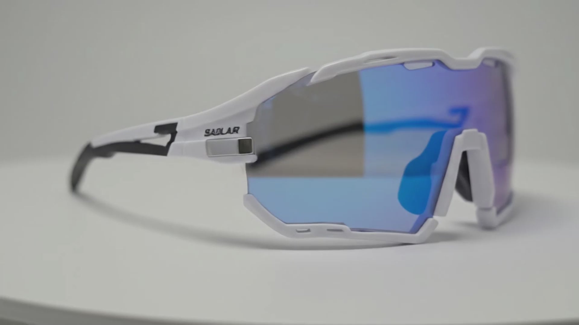 SAOLAR Rapture ICE sports sunglasses featuring blue REVO mirrored lenses, ventilation holes, and rubberized temple tips against white studio background.